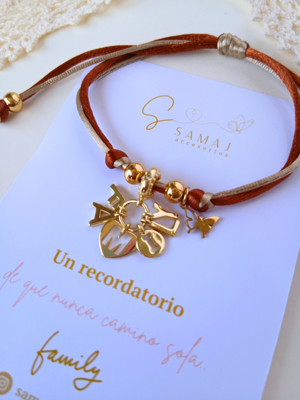 Pulsera ajustable hilo satinado con dije family con baño de oro.